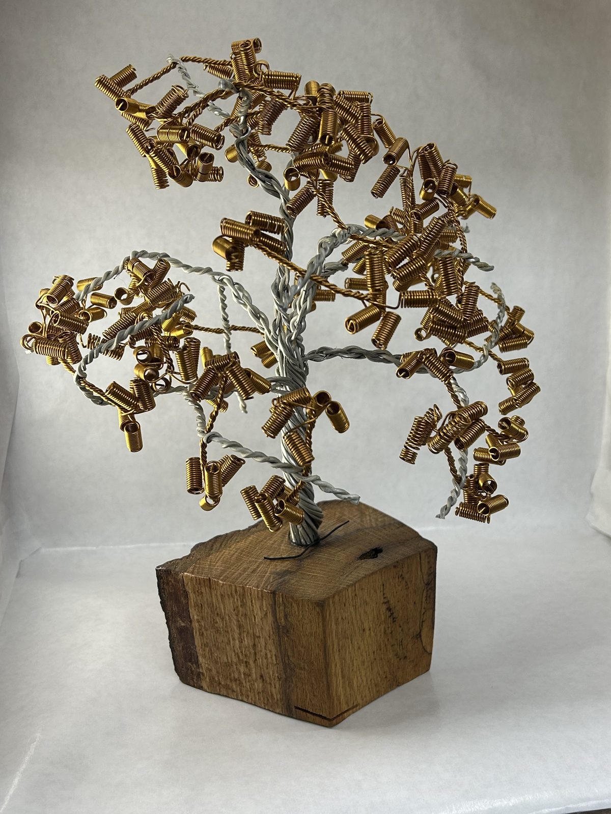 Wire bonsai with gold leaves on an oak base