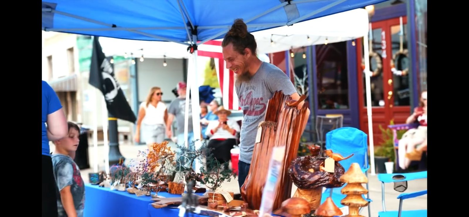Charles Shill smiling at his market booth in Woodruff, South Carolina, surrounded by his handmade wood pieces